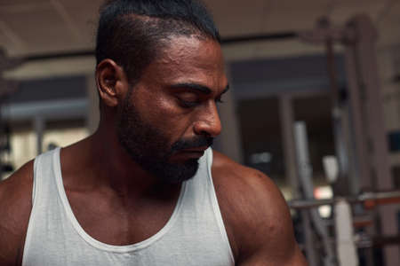 photo in profile of an attractive sports man who stands in the gym and looks down. High quality photoの写真素材