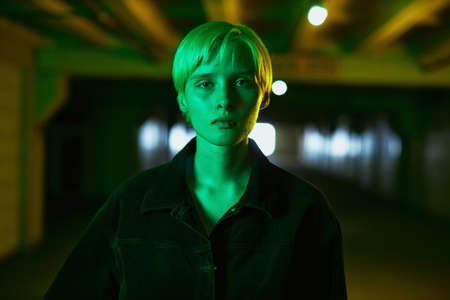 portrait of a girl in a black shirt and with a short haircut who stands in an empty parking lot in a...