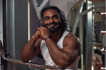 a muscular man with a beautiful skin color stands at the gym smiling and looking directly into the camera. High quality photoの写真素材