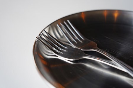 Stainless steel plate and fork on white table