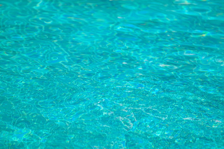 Blue water in swimming pool background. Swimming pool with sun reflections.
