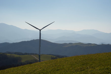 Wind Turbines on a hillside with blue sky in the backgroundの写真素材