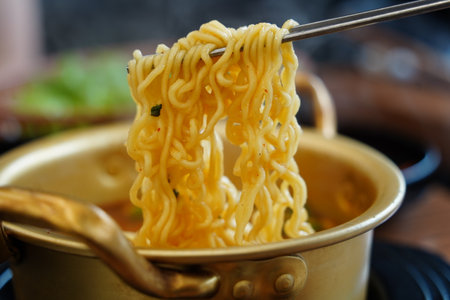 Spicy Korean instant ramen noodles in a traditional pot, lifted with chopsticks.