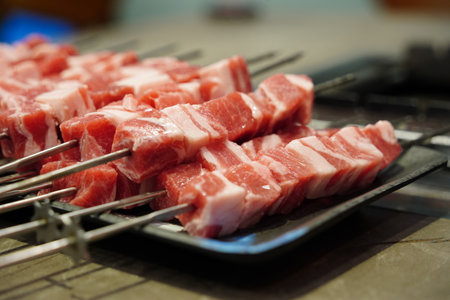 Skewers of lamb being grilled on charcoal grill in a restaurantの写真素材