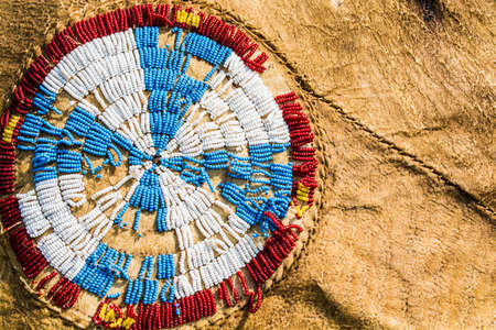 Red, white, blue and yellow Native American beads are sewn in a cross pattern on a buffalo hideの写真素材