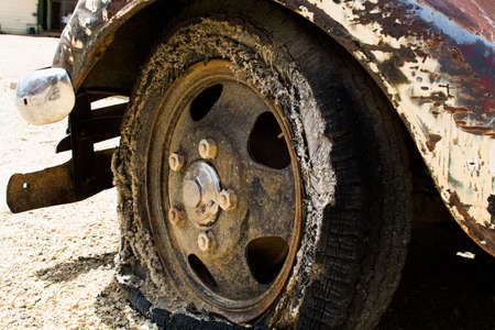 A worn, flat vintage tire mounted on an antique truckの写真素材
