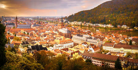 A landscape view of the city of Heidelberg, Germany taken during a Fall evening showing the city's bridge over the Neckar river, cathedrals and Fall foliage in the backgroundの写真素材
