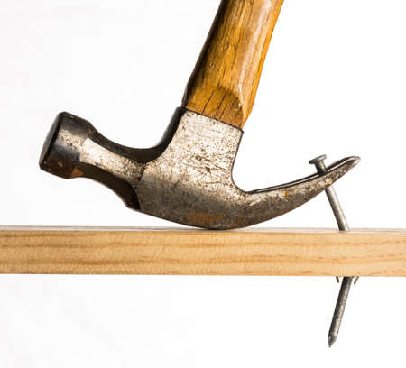 A claw hammer is shown removing a large galvanized nail from a piece of woodの写真素材
