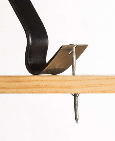 A pry bar is shown removing a large galvanized nail from a piece of woodの写真素材