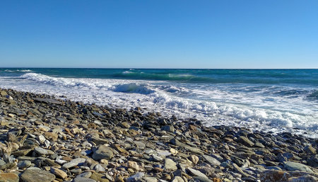 Panorama image of a beach or bay on the atlantic ocean with stones and waves a blue sky with clouds on a sunny day in summerの写真素材
