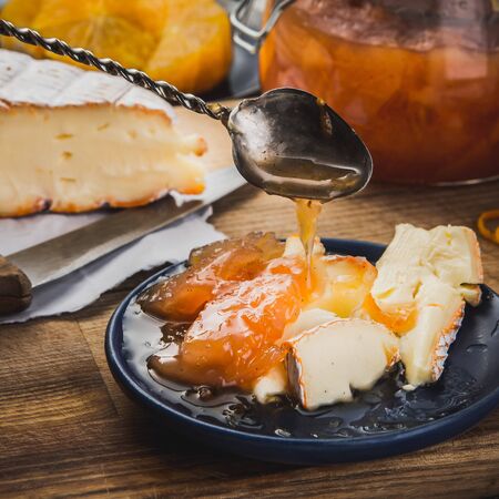 Still life with  the pieces of cheese and confiture on the blue plate and the antiquarian spoonの写真素材