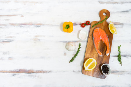 Slice of salmon with lemon, rosemary and pepper on a wooden trayの写真素材