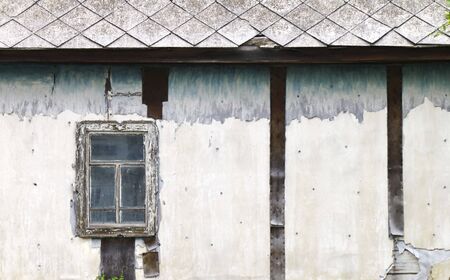 The old damaged house with a window and tiled roofの写真素材