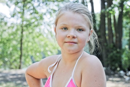 Young blond girl in a bathing suit on a background of treesの写真素材