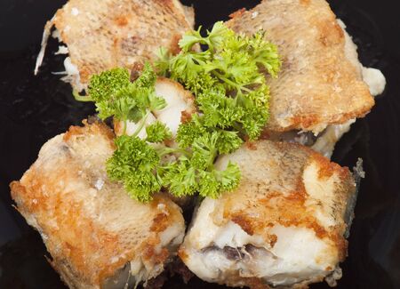 fried fish on a plate decorated with parsley