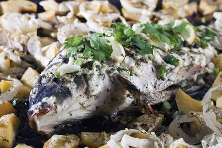 Roasted carp with potatoes and onions.