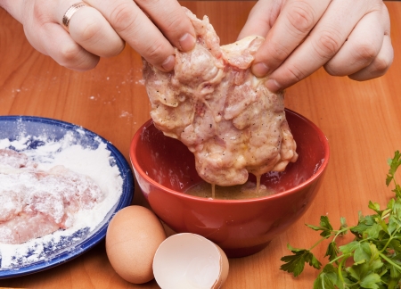 Cooking chicken thighs with a chop. Dipping egg with spicesの写真素材