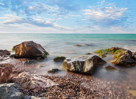 sea, sea stones, pebbles, sky with cloudsの写真素材