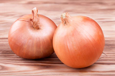 Two fresh ripe onions on a wooden boardの写真素材