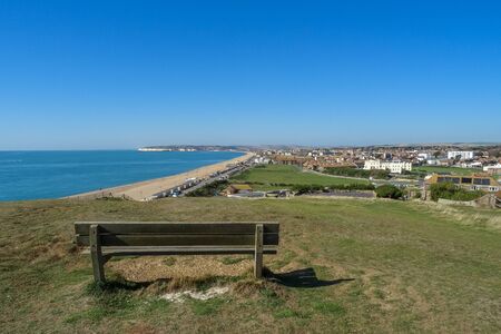 An empty park bench on Seaford Head Sussex, UK,  looking towards the town on a sunny day