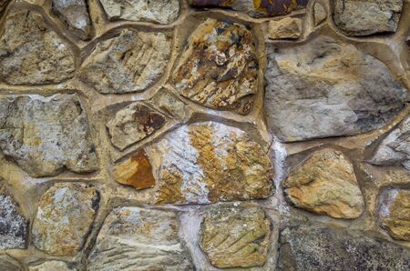 A close-up of an ornate stone wall with random shapes and sizes, pattern, texture, background in landscape formatの写真素材