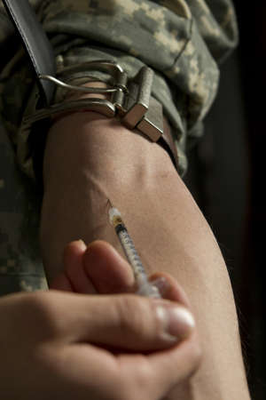 Military man injecting heroin into armの写真素材
