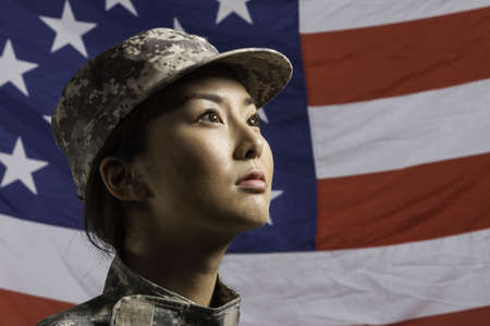 Asian-American military woman pictured in front of US flag, horizontal