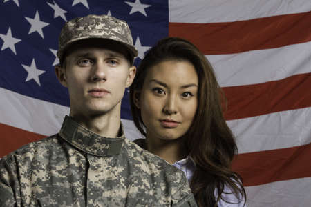 Military man and his wife in front of US flag, horizontalの写真素材