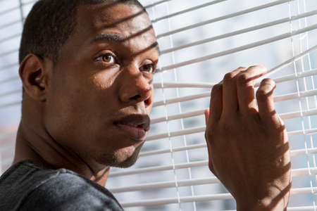 Young black man looking out window, horizontalの写真素材