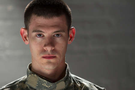 Military man looks serious in dark room, horizontal
