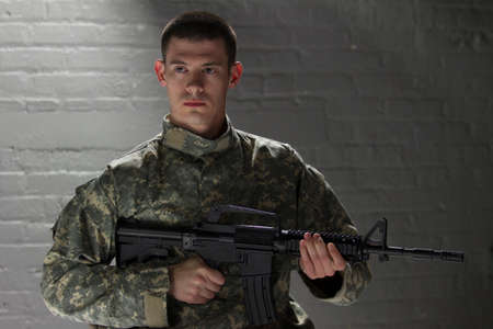 Military man holding assault rifle, horizontal