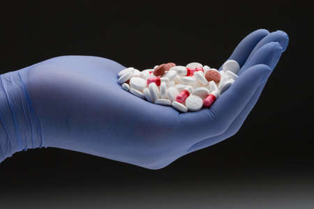 Medical personnel holding a handful of prescription pills, horizontal