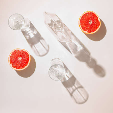 Modern composition with fresh grapefruit,  glasses and bottle on bright background. Minimal flat lay concept.の写真素材