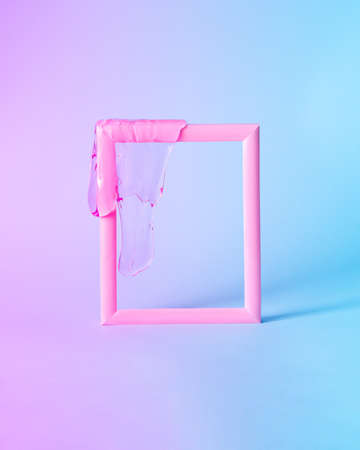 Minimal layout made with pink frame and glitter slime on it. Blue and purple gradient lights....