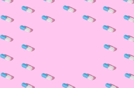 Creative pattern made with blue-white pills on pink background. Minimal sunlit print. Copy space.の写真素材