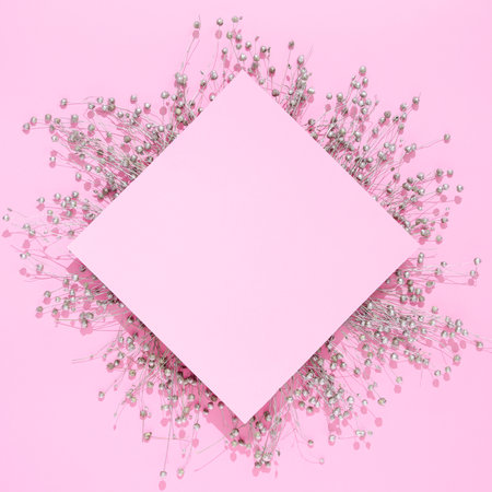 Silver dry flowers with pink paper card note on pink background. Creative flat lay concept with negative space.の写真素材