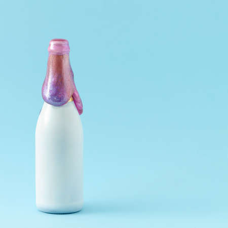 White champagne bottle with purple glitter slime on it. Minimal party concept on pastel blue background.の写真素材