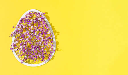 2021 Easter composition with egg shaped white frame and purple and violet flowers on illuminating background. Minimal holiday concept with copy space.の写真素材