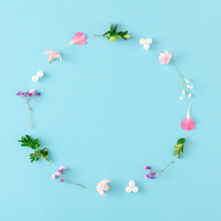 Creative spring layout made of colorful flowers, leaves and pearls on pastel blueの写真素材