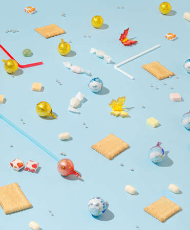 Creative pattern made with colorful candies, chocolate and cookies on pastel blue background. Minimal party concept.の写真素材