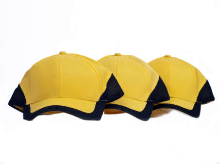 Three yellow baseball caps with black fieldの写真素材