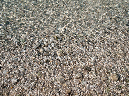 transparent water surface and sea stones on bottom 