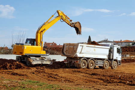 industrial excavator loading tipper truck on construction siteの写真素材