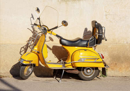 yellow retro motorcycle standing against wallの写真素材