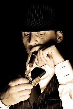 young gangster with hat smoking cigar, studio shot