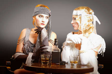 two pretty flapper girls sitting in the barの写真素材