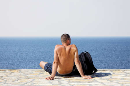 young man sitting and relaxing on coastlineの写真素材
