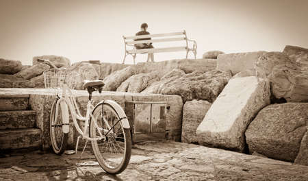 young girl sitting on the bench with her bicycleの写真素材
