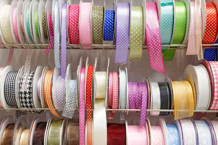 various colorful gift ribbon rolls on rack