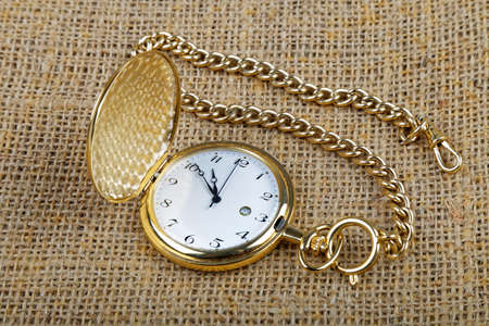 old golden pocket watch on burlap background